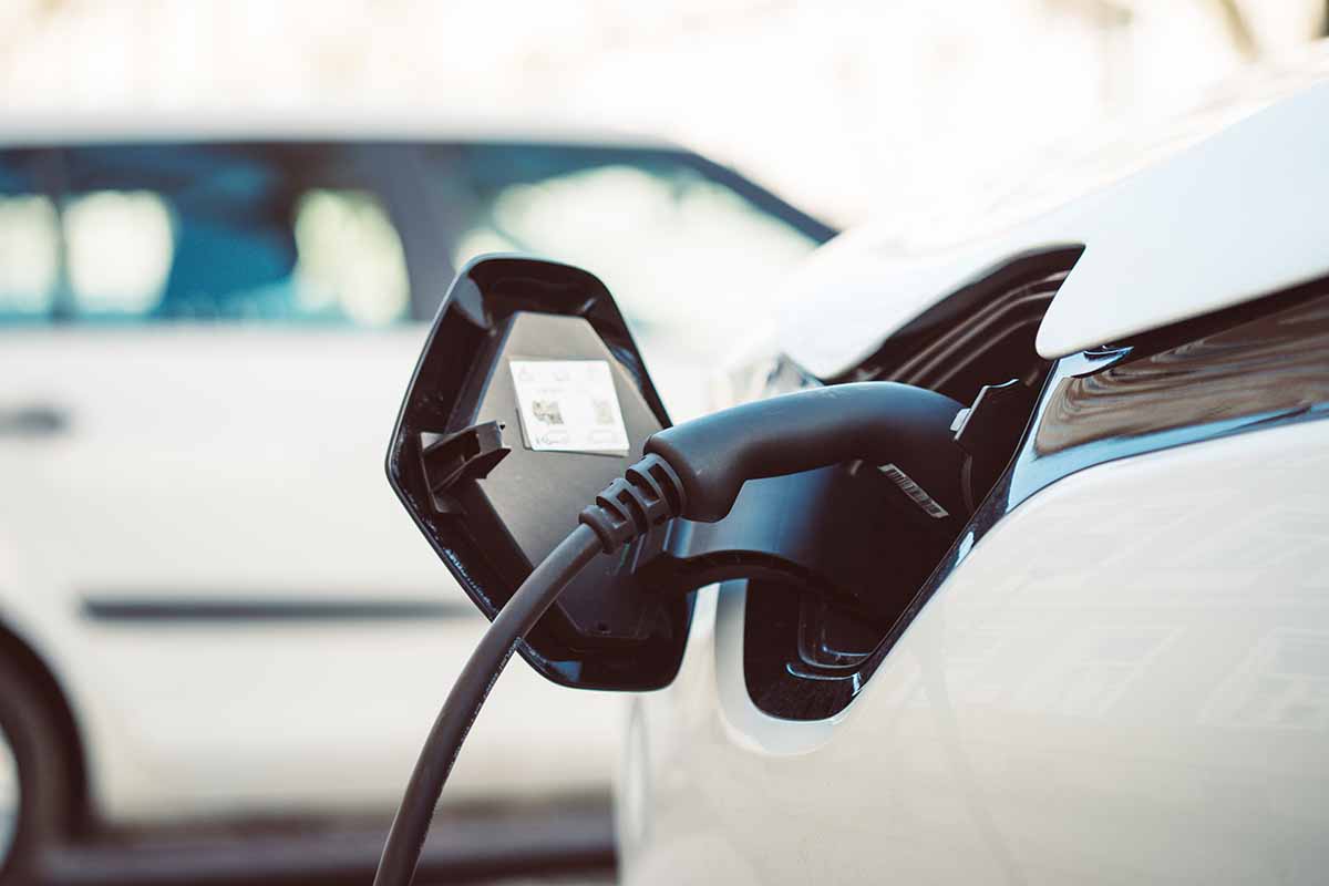 Car-Plugged-Into-EV-Charger EV-Charger Connected to White Sedan